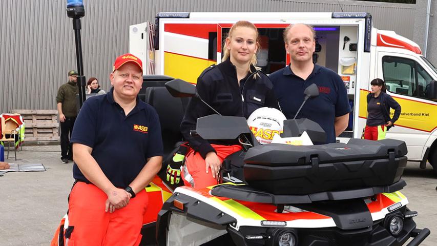 Eric Oldag sowie Svenja und Patrick Kramer (von links) mit ihrem Quad, das im Regionalverband Stormarn-Segeberg Dienst tut und ein Hingucker beim Fest des Kieler ASB war.